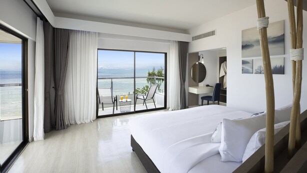 Ein modernes Hotelzimmer mit einem großen Bett, einem Schreibtisch und Blick auf den Ozean.