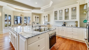 A spacious kitchen with a large island, white cabinetry, and a view of the outdoors. - Luxurious Ocean Front Home w/ Rec Room (Hilton Head Island)