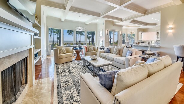 A spacious living room with a fireplace, large windows, and a view of the ocean. - Luxurious Ocean Front Home w/ Rec Room (Hilton Head Island)