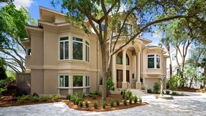 A large, modern house with a spacious driveway, multiple windows, and a well-maintained garden. - Luxurious Ocean Front Home w/ Rec Room (Hilton Head Island)