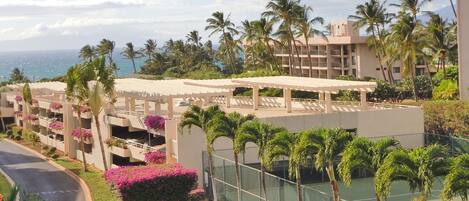 A resort with multiple-story buildings, a tennis court, and a view of the ocean.