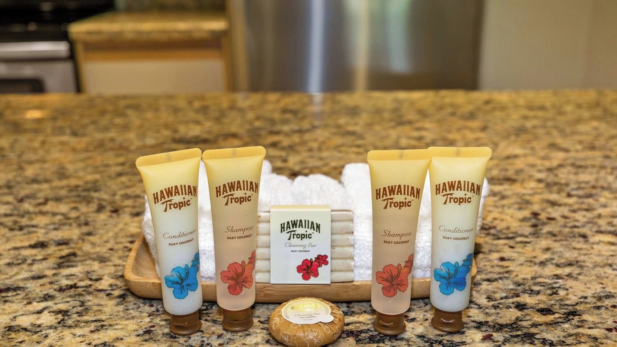 A countertop with five tubes of Hawaiian Tropic products, a cleansing bar, and a coconut.