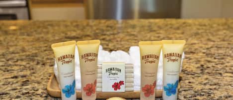 A countertop with five tubes of Hawaiian Tropic products, a cleansing bar, and a coconut.