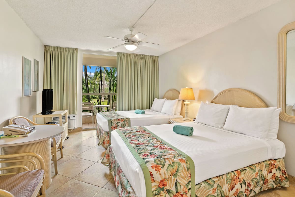 Quarto de hotel com duas camas, uma escrivaninha, uma cadeira, uma televisão e uma janela com cortinas.