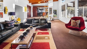 Una sala de estar moderna con un sofá de cuero negro, un sillón rojo y una mesa de centro con libros.