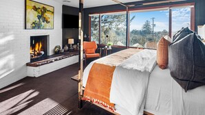 Un dormitorio con chimenea, una cama grande, vistas al exterior y un diseño moderno.