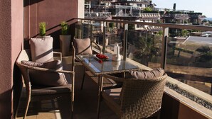 A balcony with wicker furniture, a glass table, and potted plants. - Sea view Apartment Hermes (Budva)