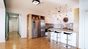 A modern kitchen with a central island, stainless steel appliances, and a bar area with stools. - Sea view Apartment Hermes (Budva)