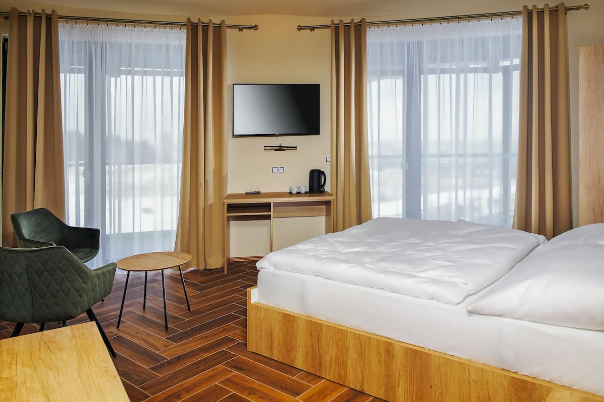 A hotel room with a bed, a desk, a chair, a television, and a coffee maker.