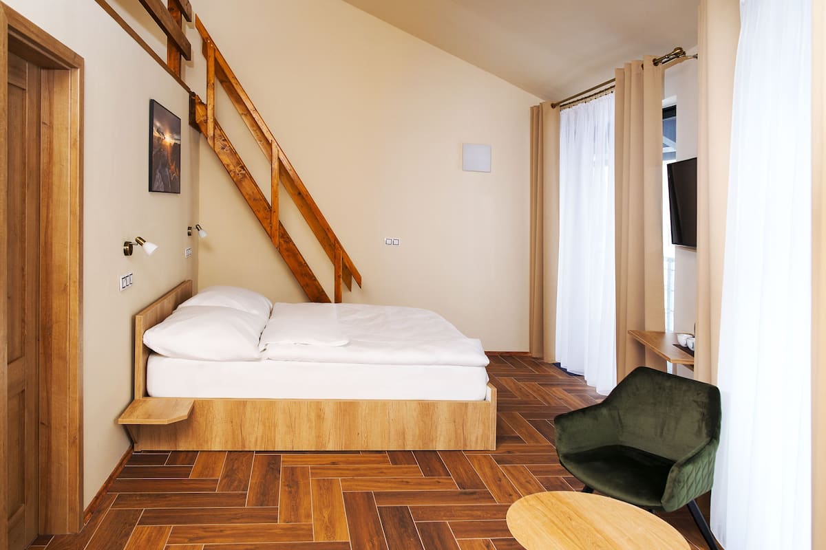 A bedroom with a wooden bed, a chair, and a herringbone-patterned floor.