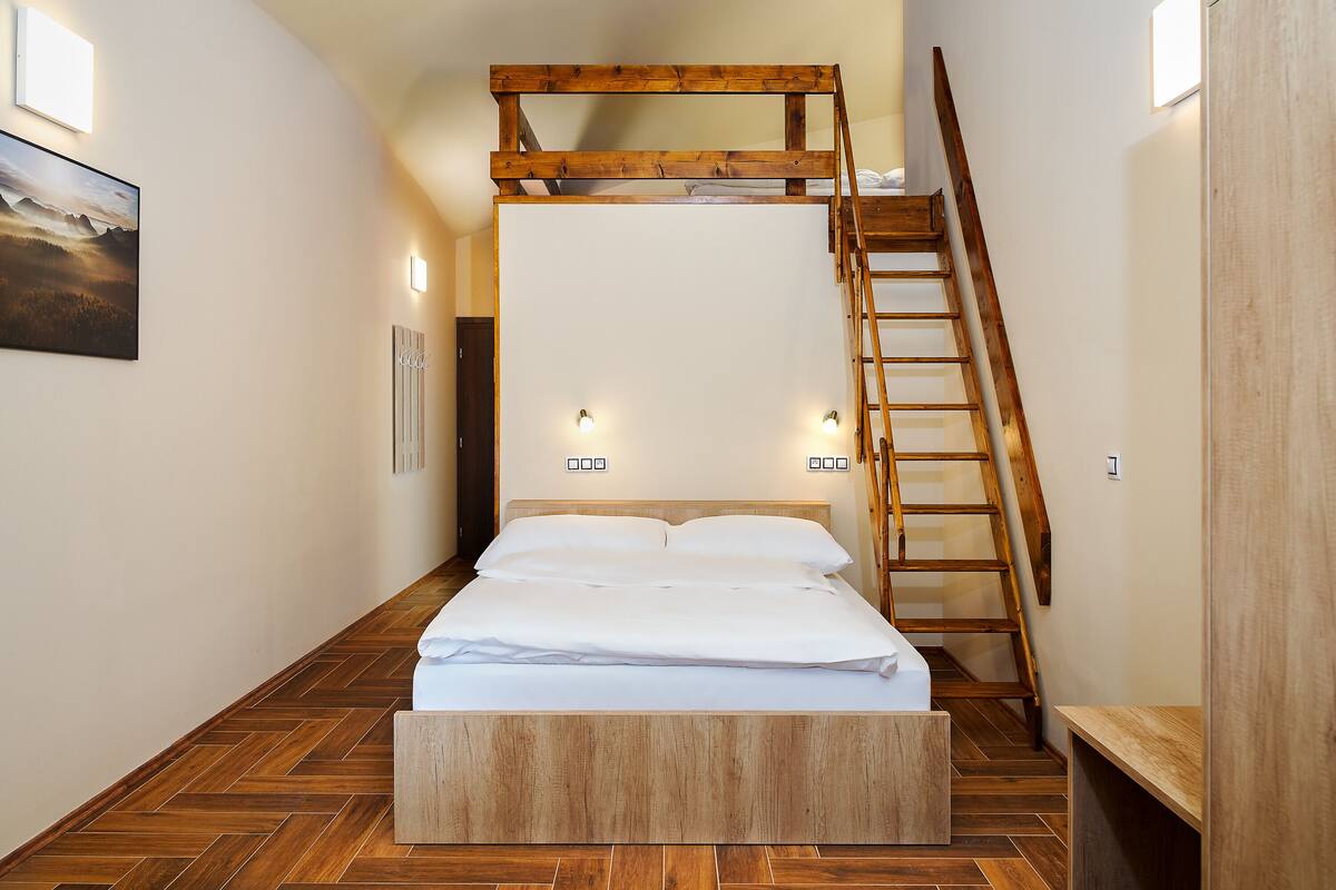 A bedroom with a bunk bed, wooden ladder, and a herringbone-patterned floor.
