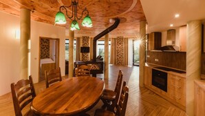 A spacious dining area with a wooden table and chairs, a built-in fireplace, and a ceiling with a decorative design. - Hotel Dymník (Rumburk)