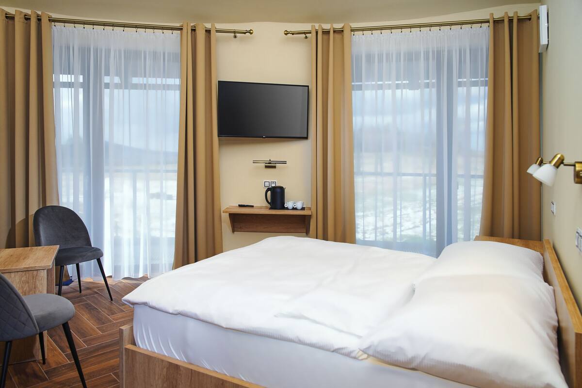 A hotel room with a bed, a desk, a chair, a TV, and a coffee maker.