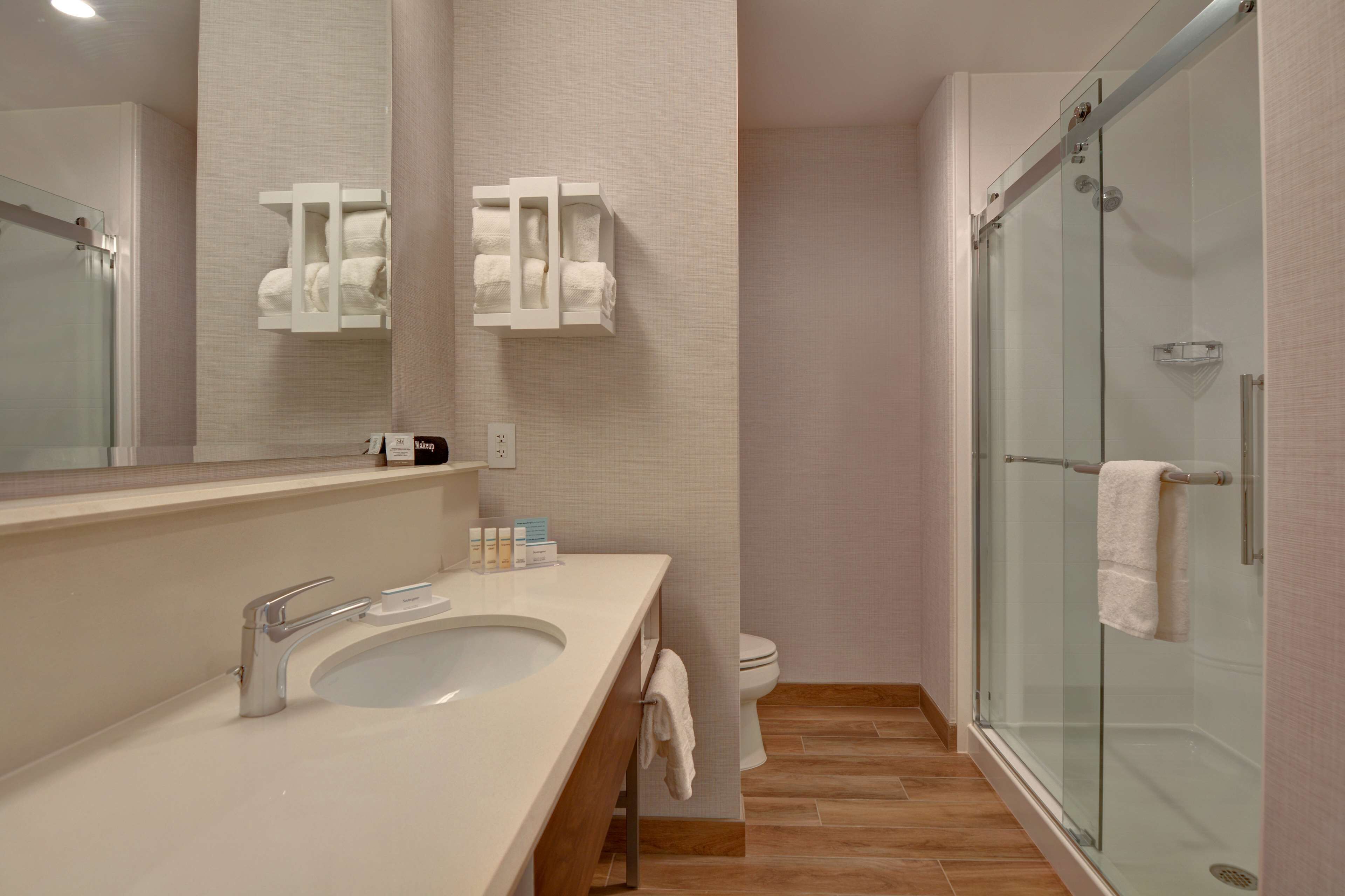 A modern bathroom with a glass-enclosed shower, a large mirror, and a white sink.