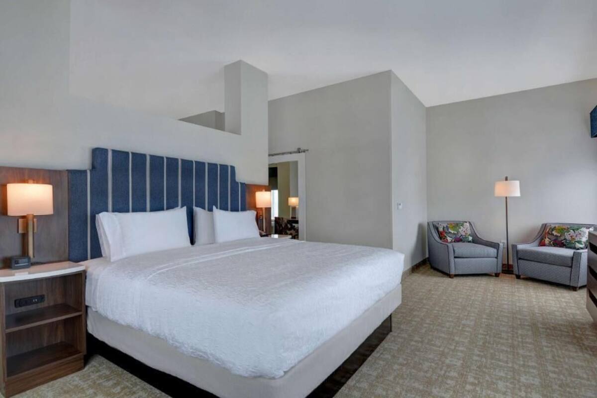 A hotel room with a large bed, two bedside tables, a chair, and a floor lamp.