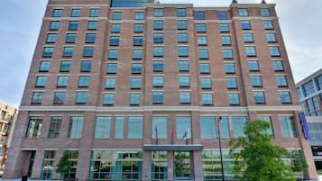 A multi-story hotel with a brick facade, large windows, and a sign reading "Hampton Inn & Suites."