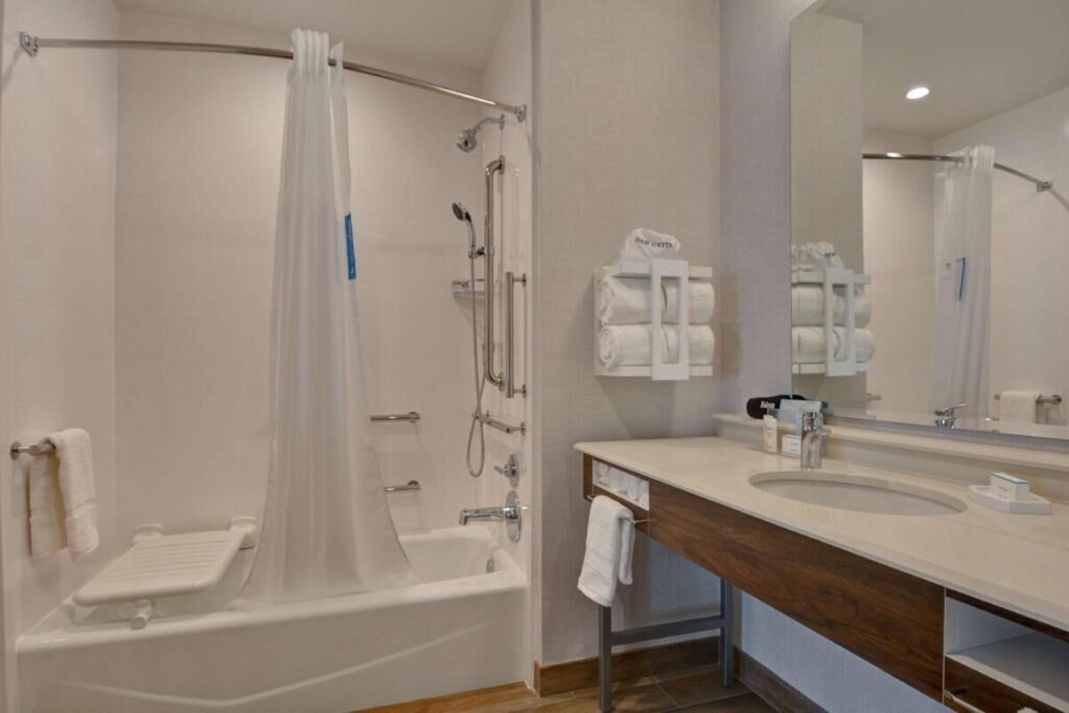 A modern bathroom with a bathtub, shower, and sink.