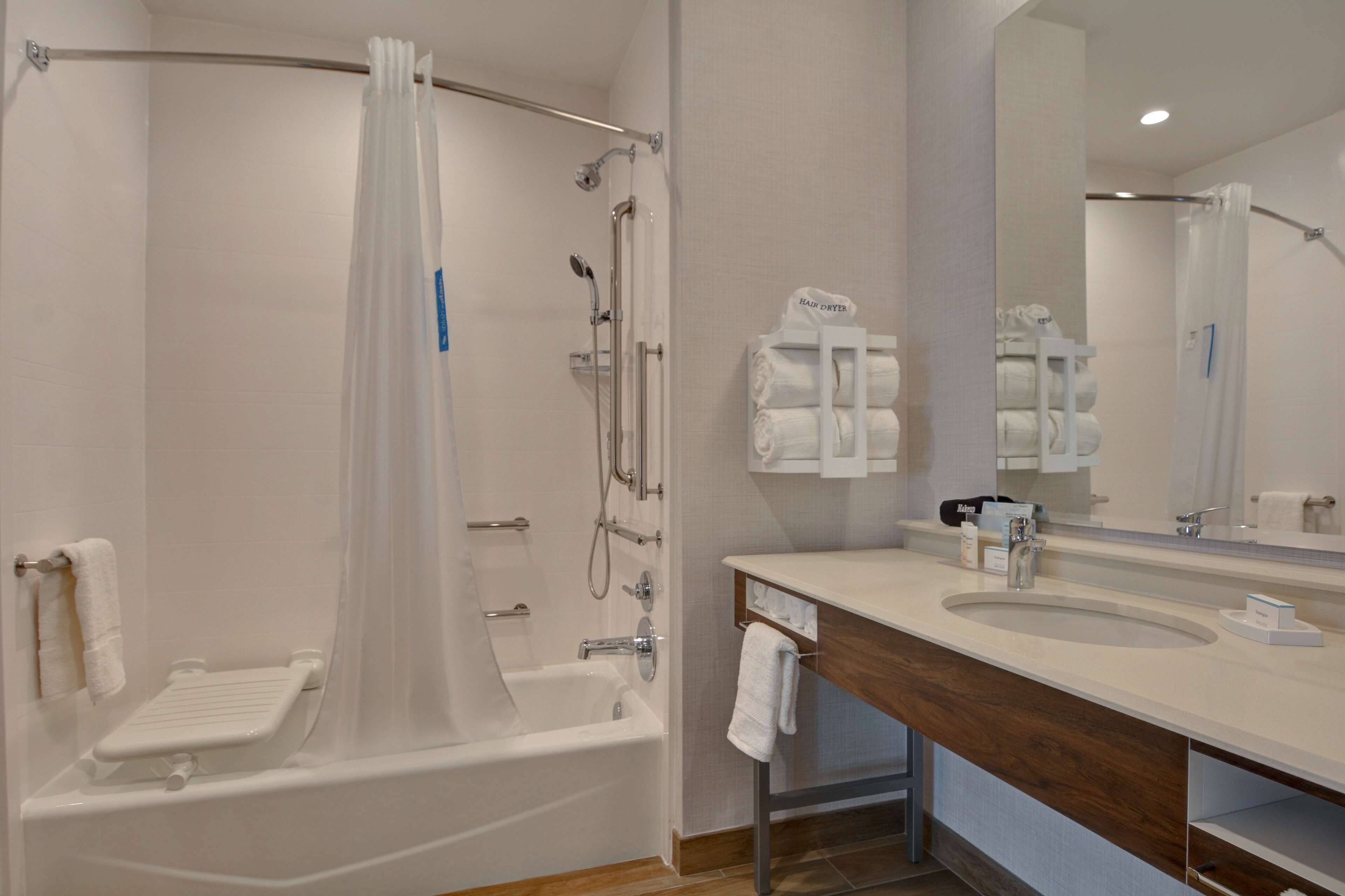 A modern bathroom with a bathtub, shower, and vanity with a mirror.