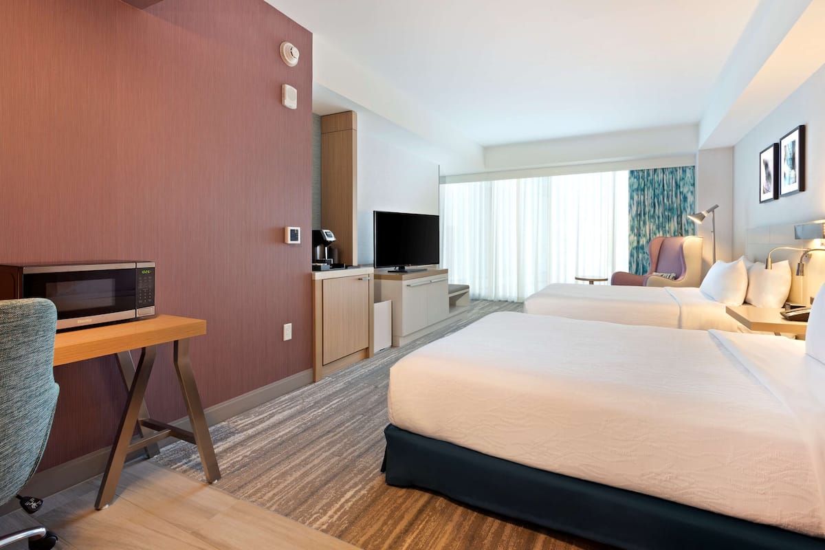 Ein Hotelzimmer mit einem Bett, einem Schreibtisch mit einer Mikrowelle, einem Fernseher und einer Kaffeemaschine.
