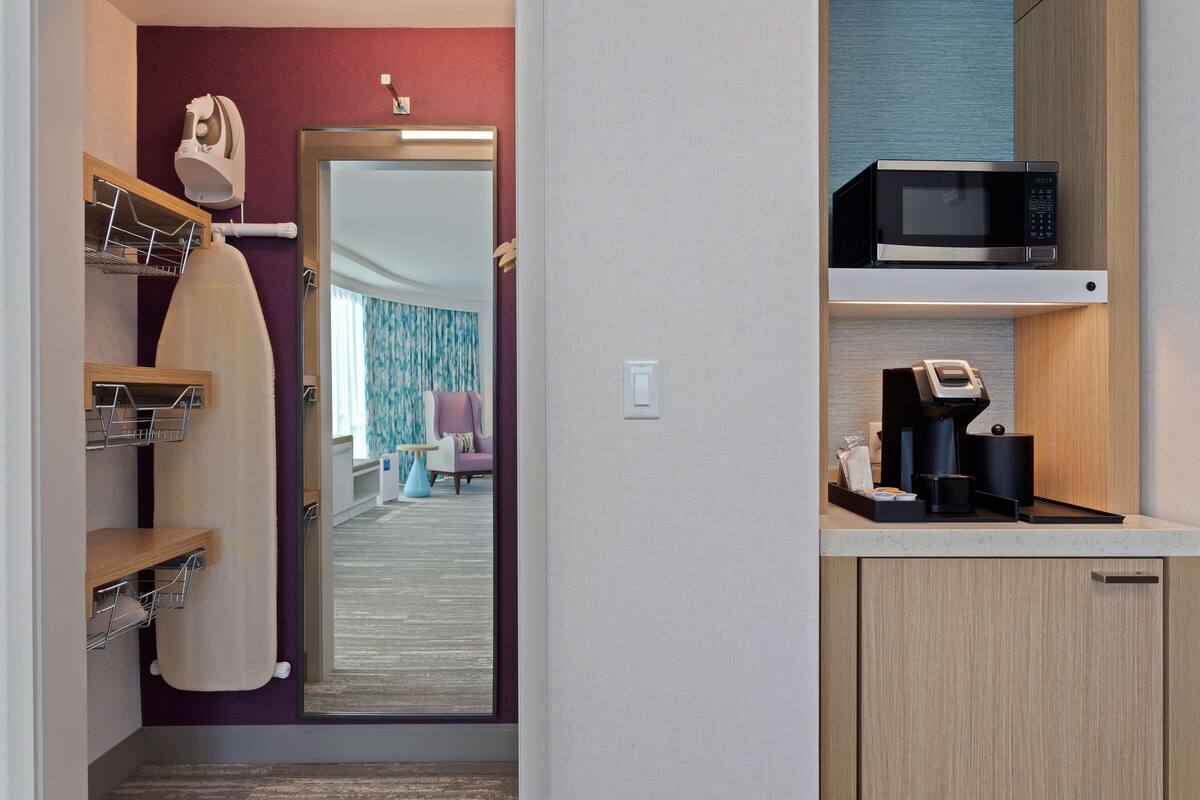 Ein kompaktes Hotelzimmer mit Küchenzeile, Fön und Mikrowelle auf der Arbeitsfläche.