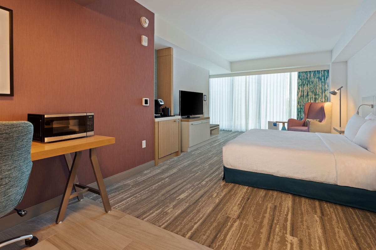 Ein Hotelzimmer mit einem Bett, einem Schreibtisch mit Mikrowelle, einem Fernseher und einem Stuhl.