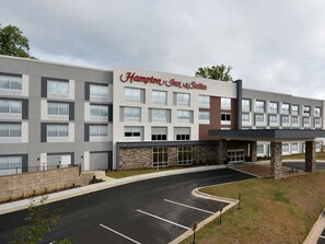 Ett Hampton Inn & Suites-hotell med en modern fasad, många fönster och en parkeringsplats.