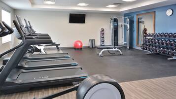 Un gimnasio con cintas de correr, balones de ejercicio y mancuernas.
