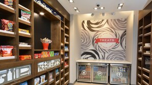 A snack and treat display area with shelves stocked with various snacks and a wall with a 'Treats' sign. - Hampton Inn & Suites by HIlton Charlotte North I 485 (Charlotte)