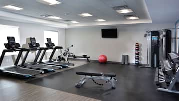 A gym with treadmills, a bench, a red exercise ball, and weight machines.