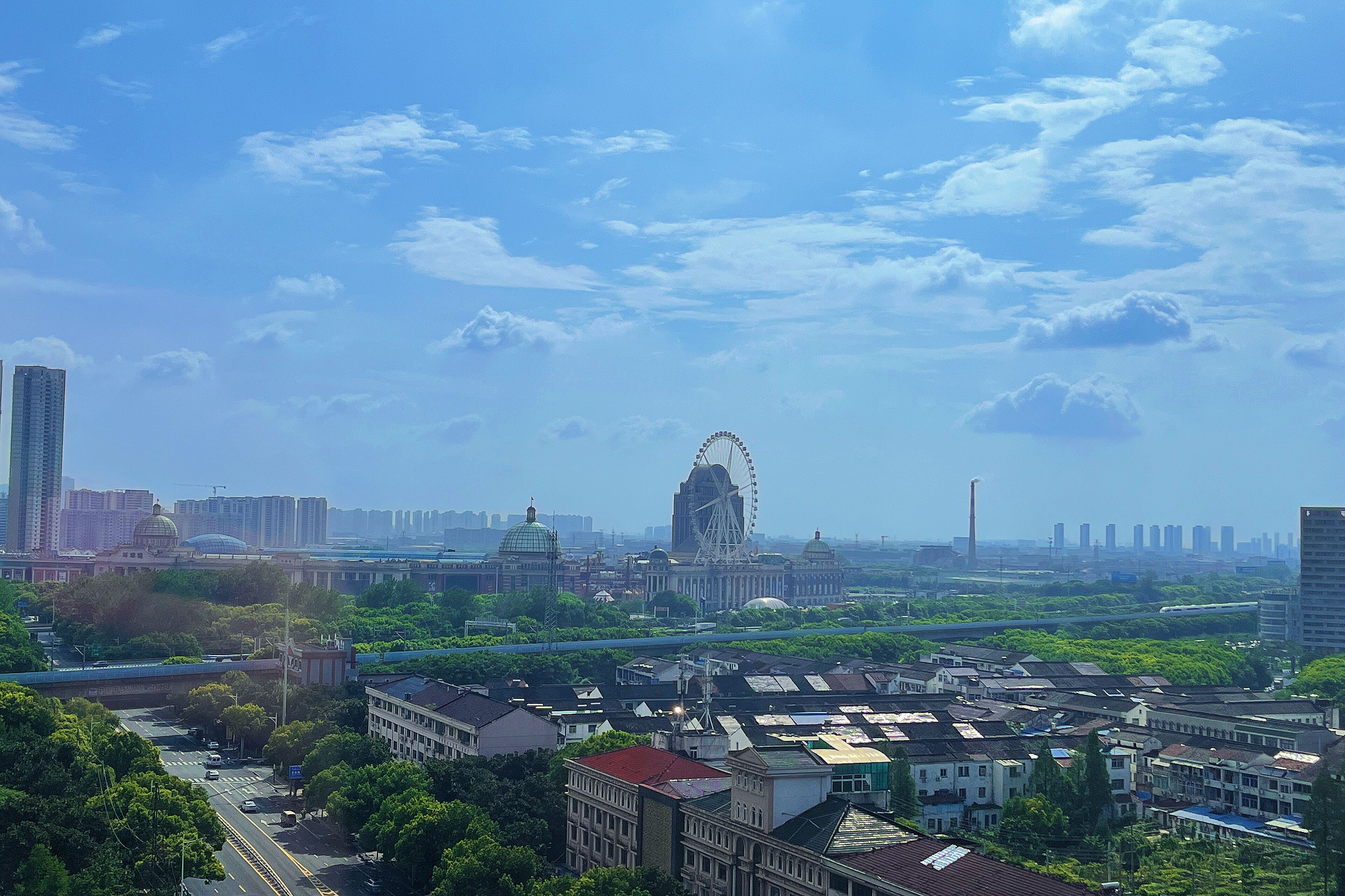 A cityscape with a prominent Ferris wheel, modern buildings, and a mix of greenery.
