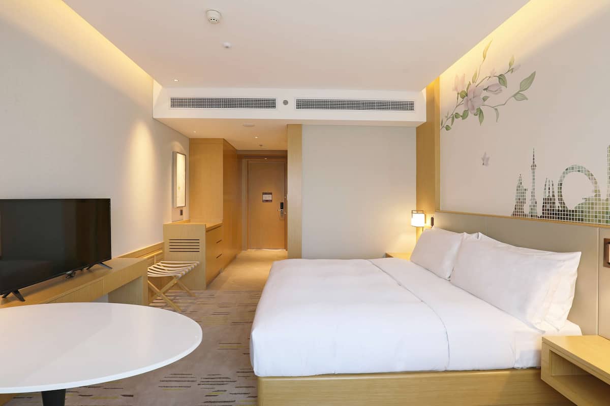 Una habitación de hotel con cama, televisión, escritorio y silla.