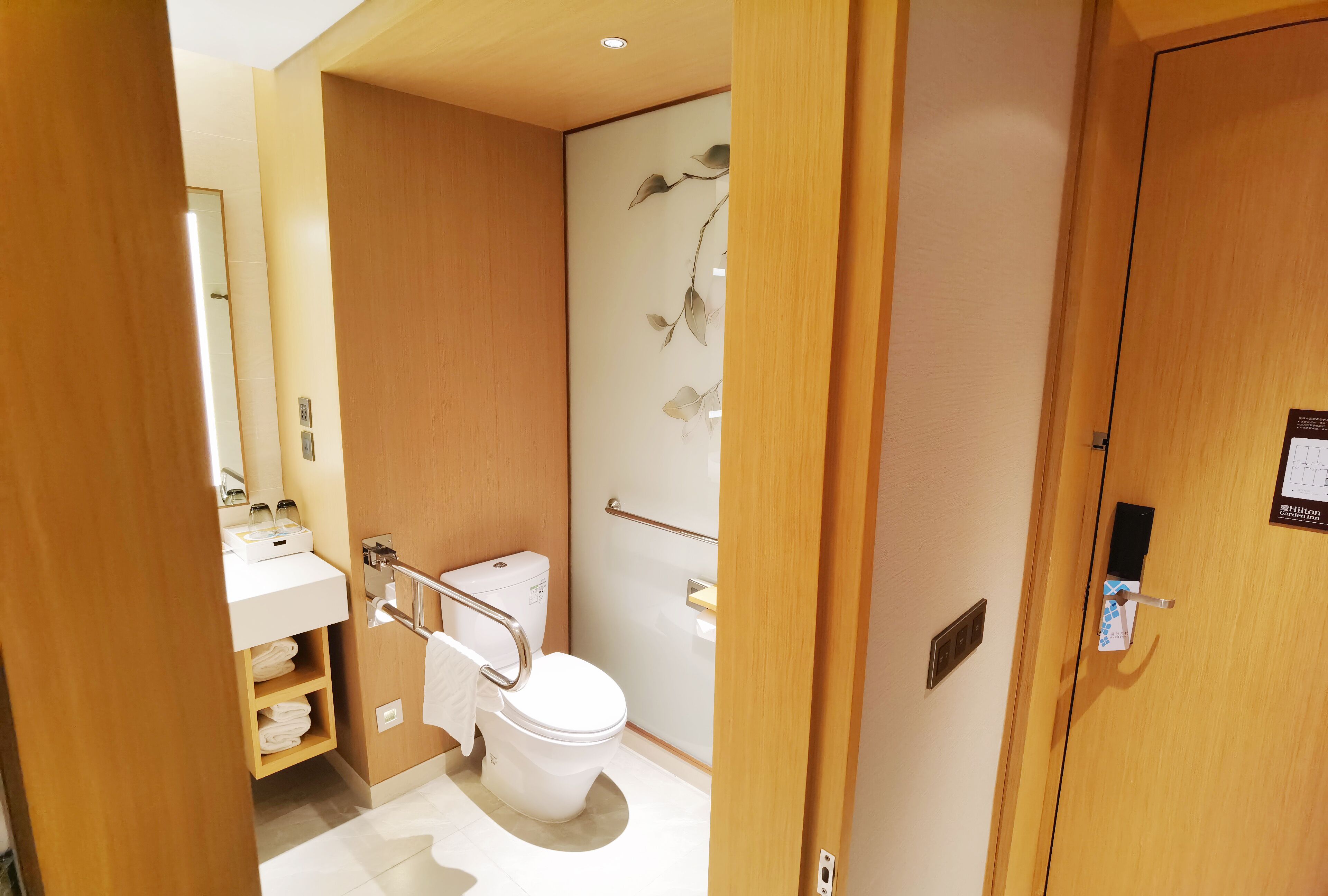 A compact bathroom with a toilet, sink, and towel rack.