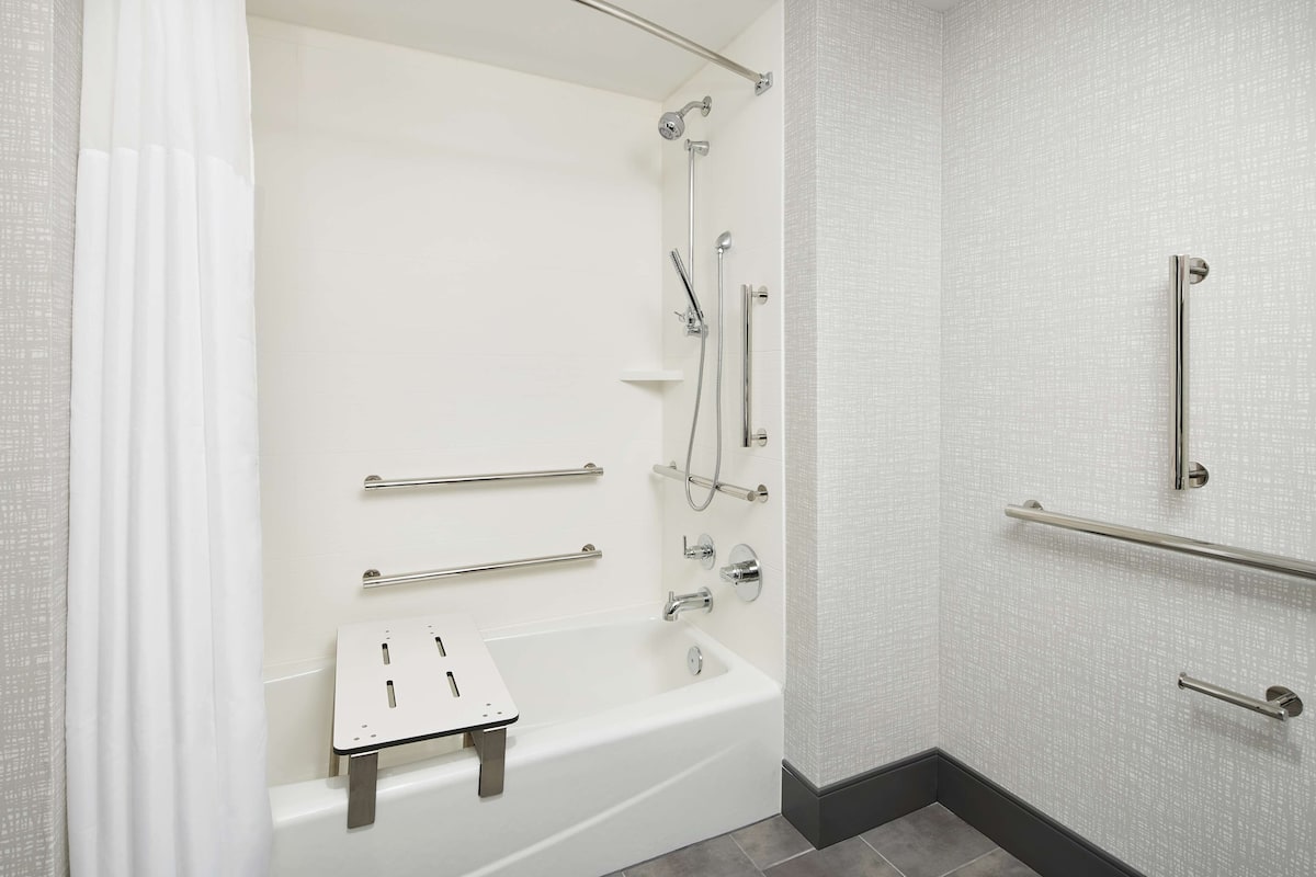 Un baño moderno con bañera, ducha y barras de apoyo.