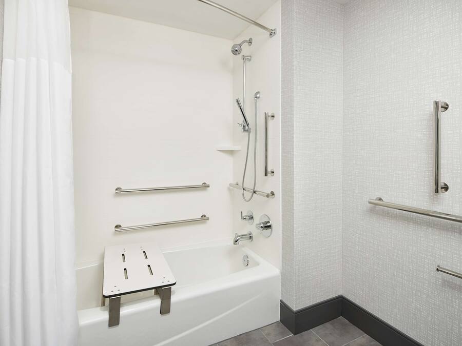 Un baño moderno con bañera, ducha y barras de apoyo.