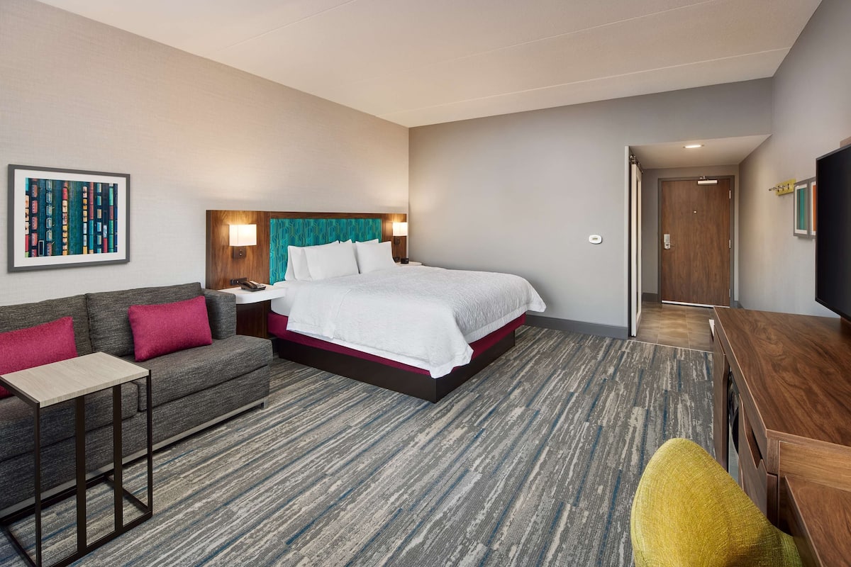Una habitación de hotel con una cama, un sofá, una mesita y un televisor.