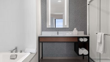 Un baño moderno con un espejo grande, un lavabo blanco y una cabina de ducha de vidrio.