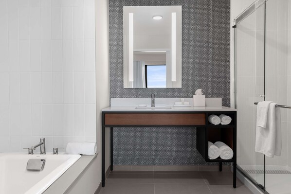 A modern bathroom with a large mirror, white sink, and a glass shower enclosure.