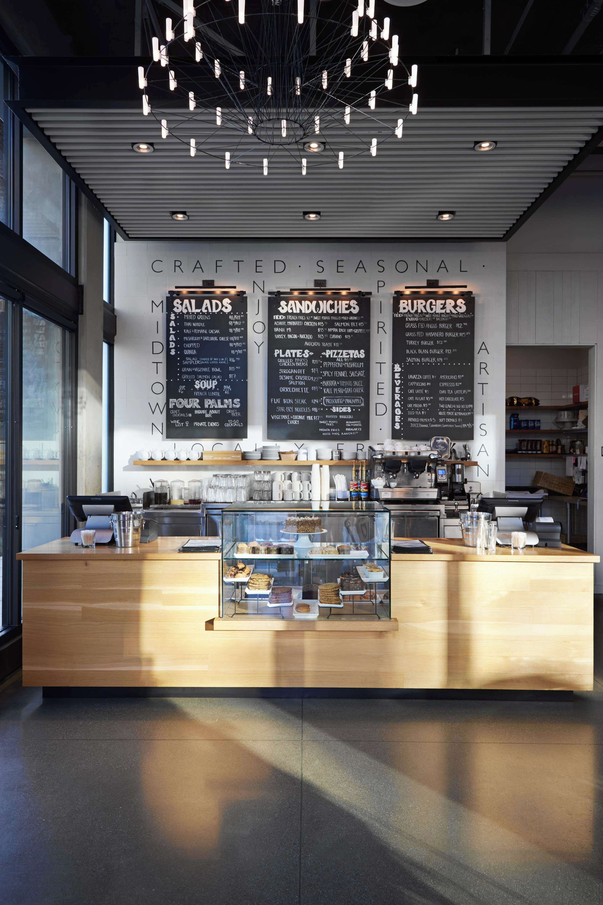 A modern restaurant interior with a wooden counter, menu boards, and a glass display case.
