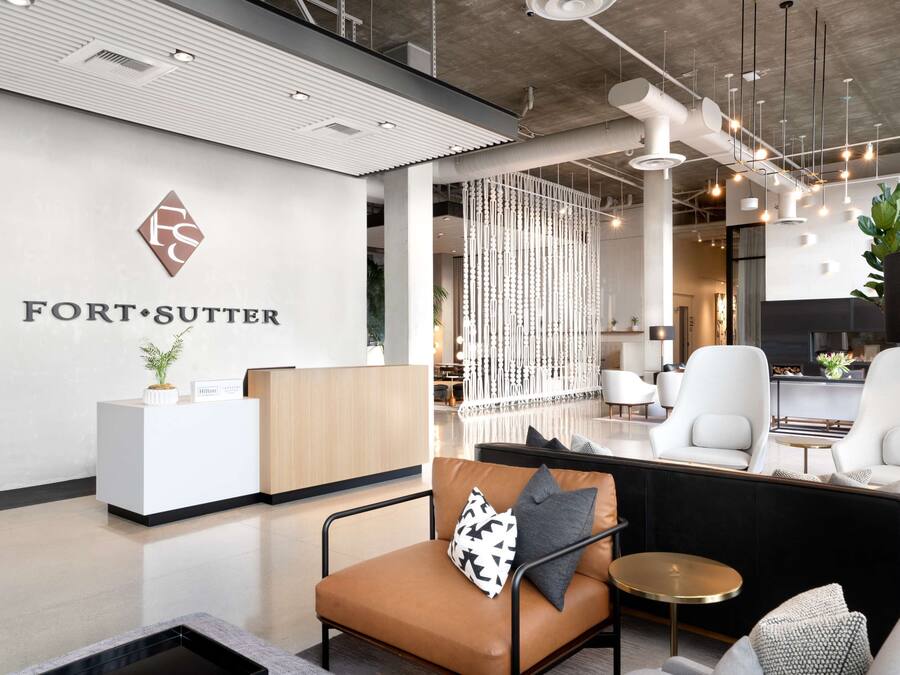 A modern reception area with a white reception desk, leather seating, and a decorative plant.
