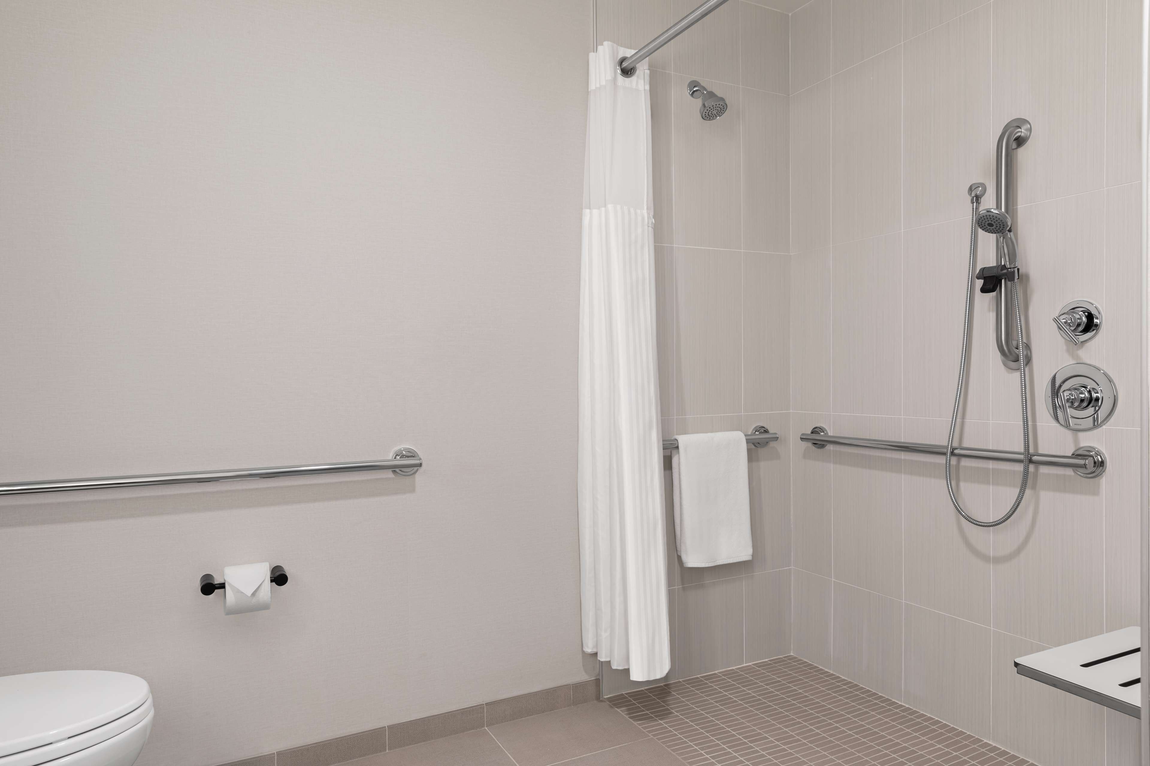 A modern bathroom with a shower, toilet, and a towel rack.