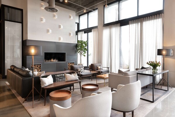 A modern living room with a fireplace, sofas, a coffee table, and a dining area.