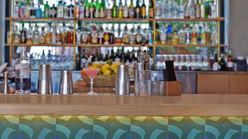 Zona de bar con taburetes, barra y estanterías llenas de botellas.