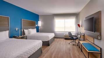 Une chambre d’hôtel avec deux lits, un bureau, une chaise, une télévision et une grande fenêtre.