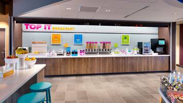 A breakfast counter with a variety of food options including eggs, waffles, and yogurt.