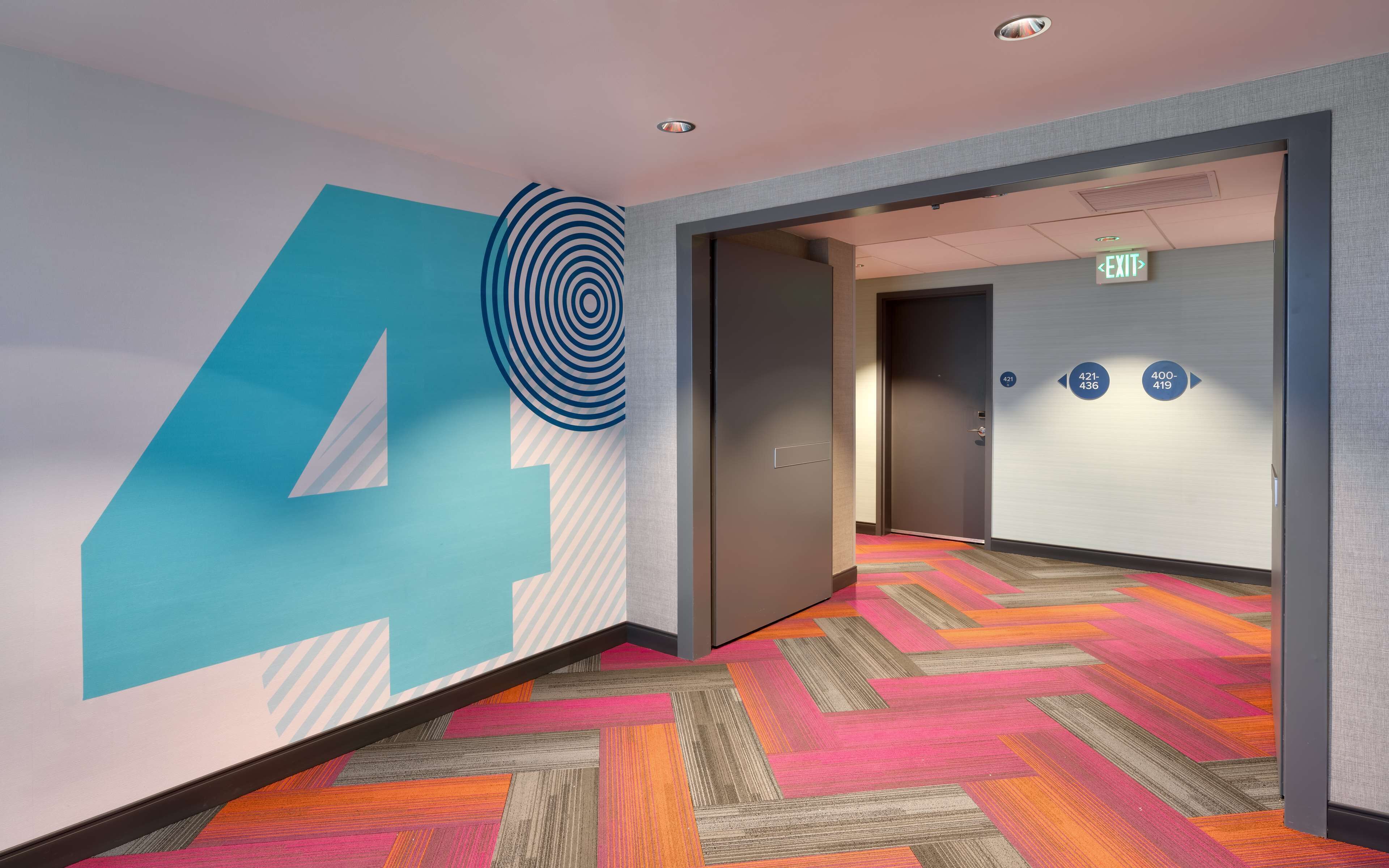 A hallway with a large number '4' mural, an exit sign, and directional arrows on the wall.