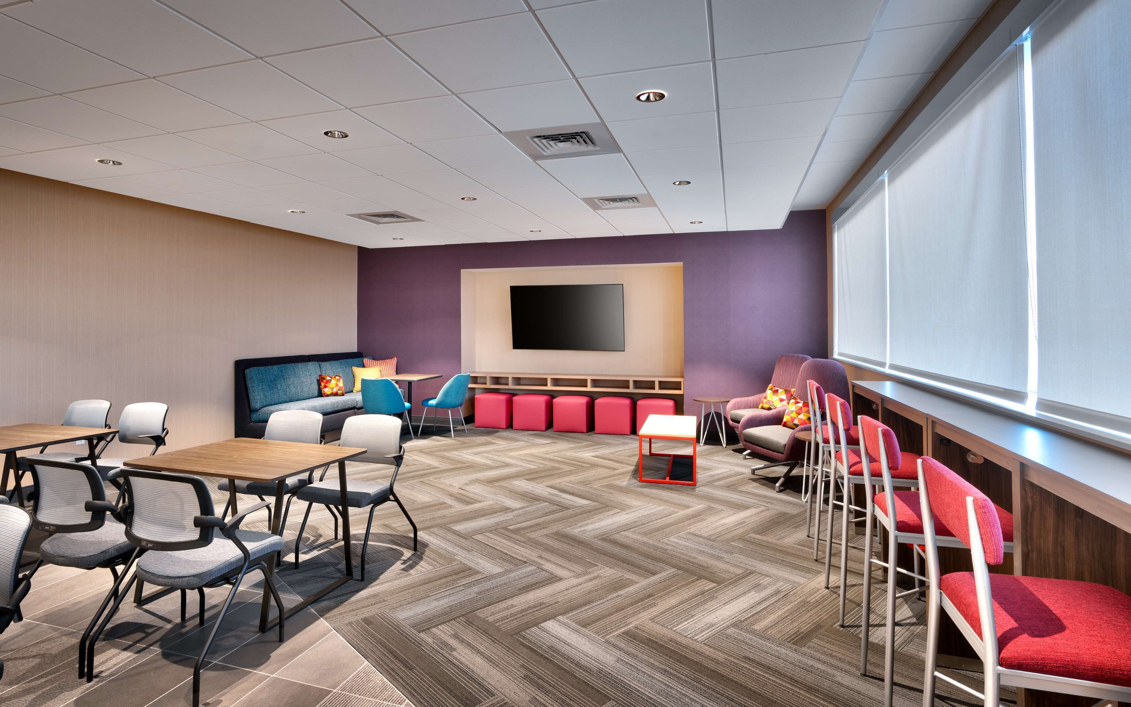 A conference room with a large screen, multiple seating arrangements, and a herringbone-patterned floor.