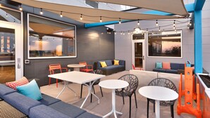 Eine Terrasse im Freien mit Sitzgelegenheiten, Tischen und Lichterketten.