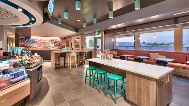Ein modernes Restaurant-Interieur mit Bar, Sitzgelegenheiten und Blick ins Freie.