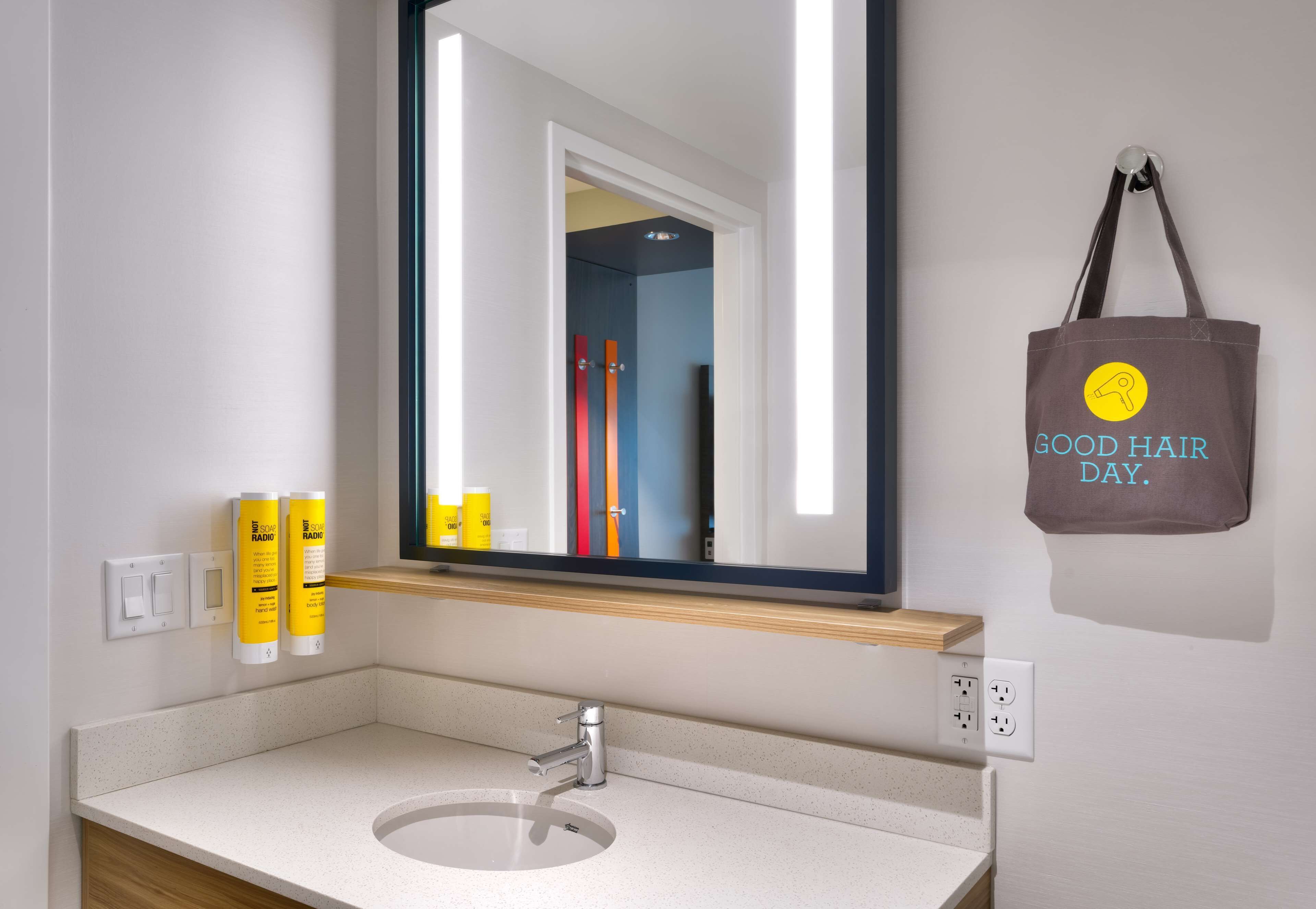 A bathroom with a white sink, a mirror, and a towel hanging on the wall.
