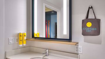 A bathroom with a white sink, a mirror, and a towel hanging on the wall.